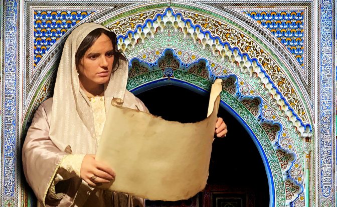 A museum exhibit of a Fatima Al-Fihri mannequin in a white robe holding a parchment scroll in front of a blue and white tiled archway.